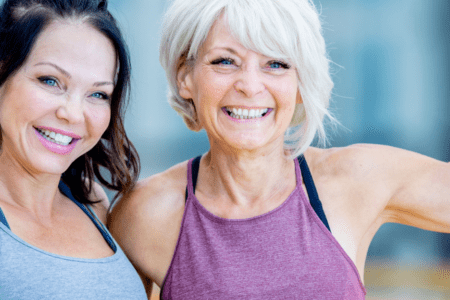 Two women flexing muscles, smiling.