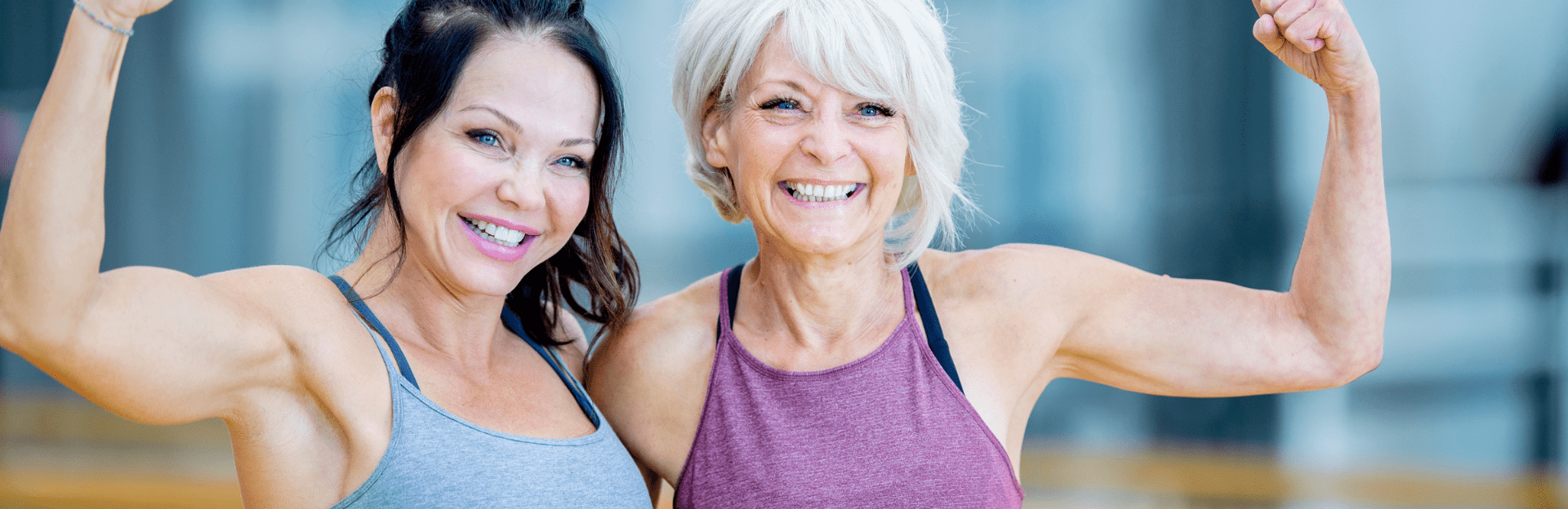Two women flexing muscles, smiling.