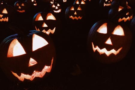 Pumpkins carved into jack-o-lanterns on display at night.