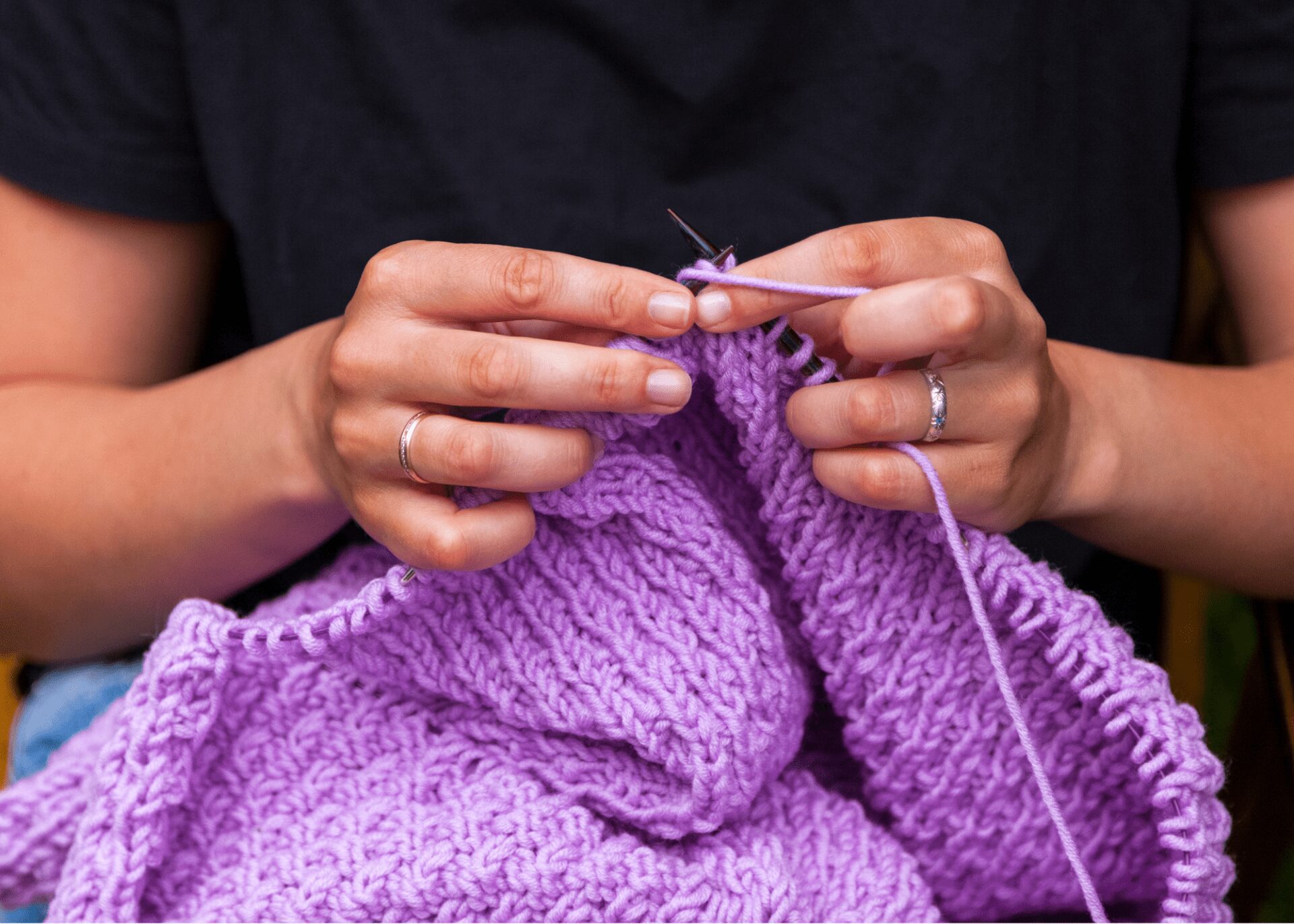 Person knitting with purple yarn