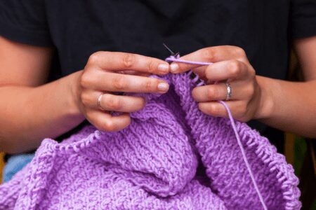 Person knitting with purple yarn