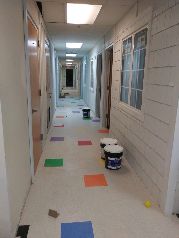 Hallway covered in multicolored floor tiles with a few items scattered on the floor.